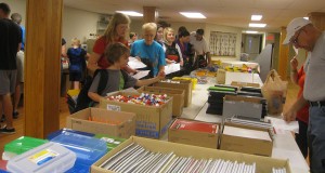 55 volunteers pick up back packs and a list of school supplies for a student
